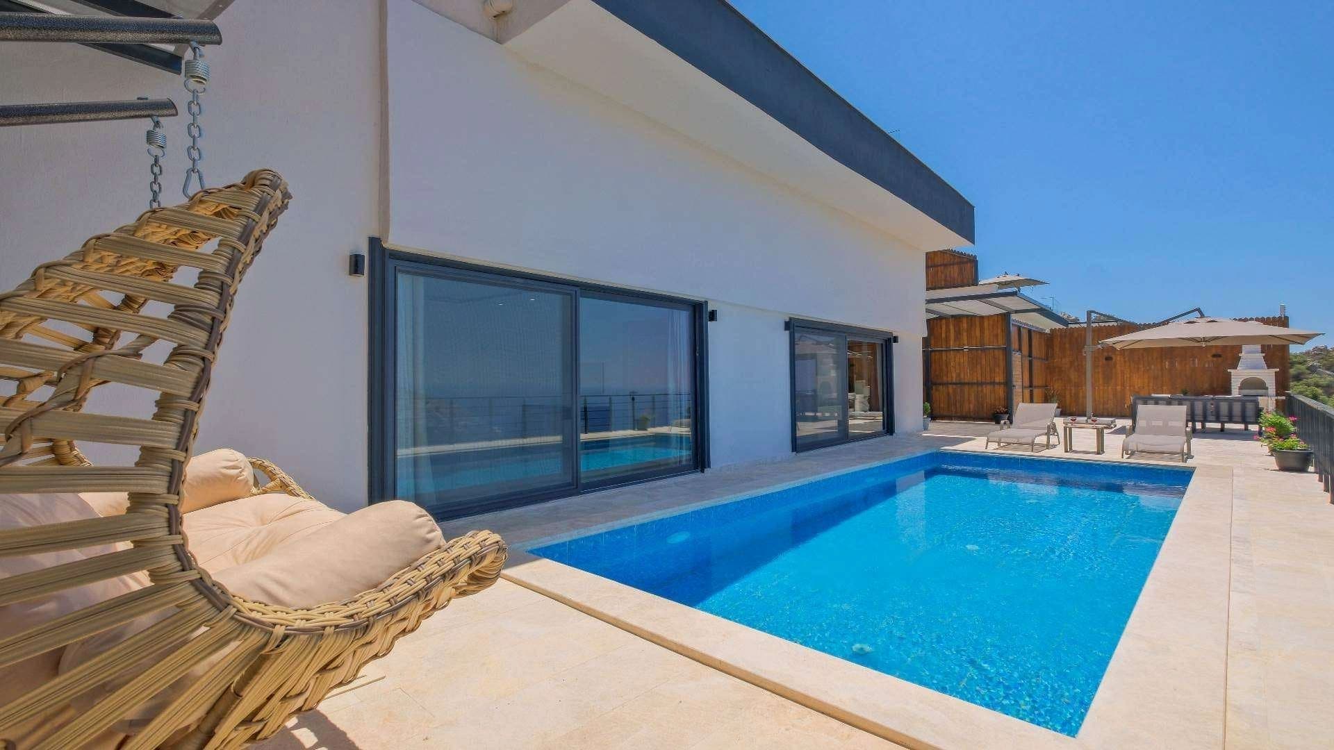 Açık havada özel havuz kenarında salıncak ve şezlonglar bulunan villa terası.
