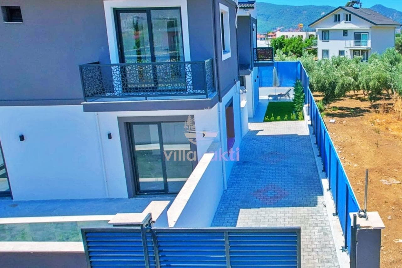 Balkonlu ve ferforje korkuluklu modern villanın dış cephesi ve bahçe yolu.