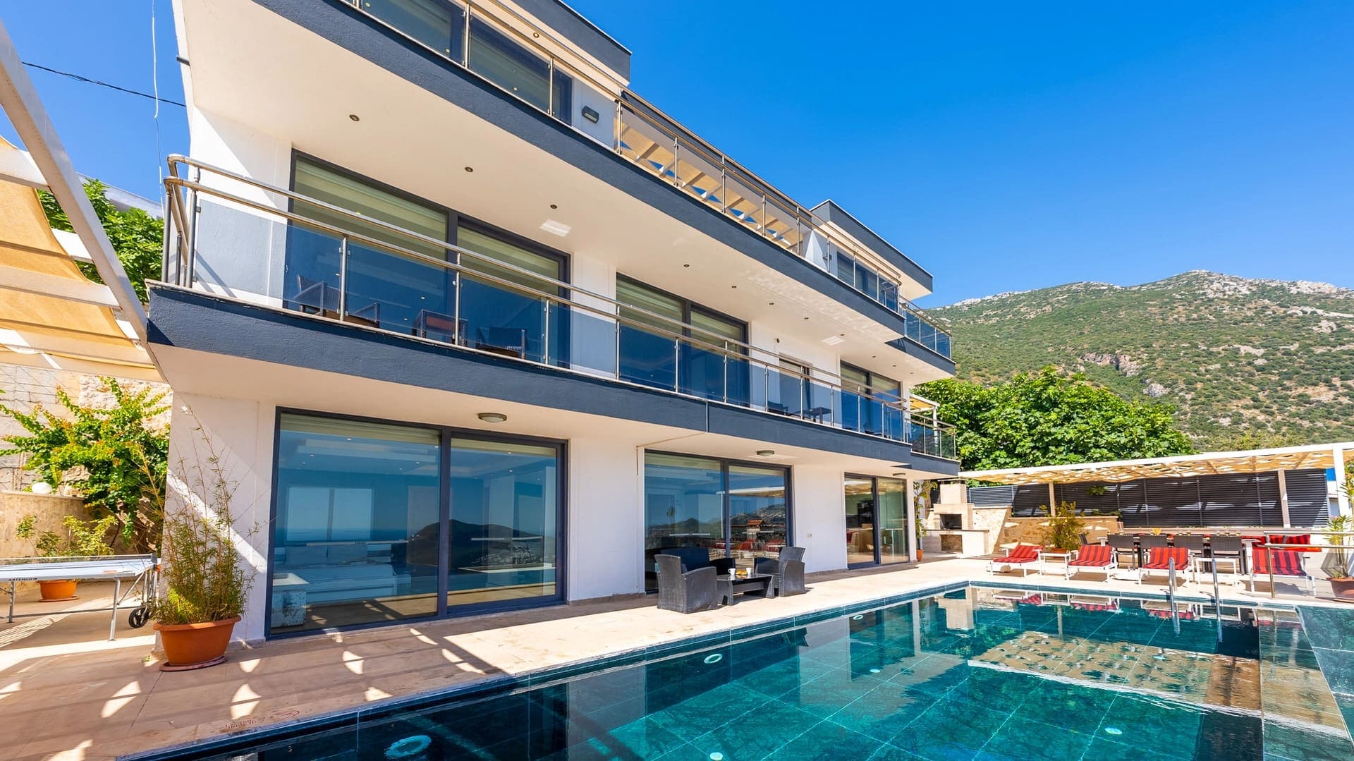 Güneşli havada havuz başındaki modern villanın dış cephesi