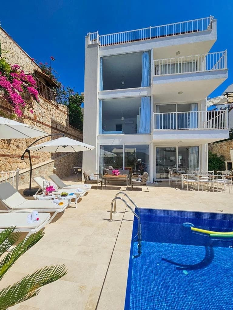 Beyaz cepheli, balkonlu ve havuzlu villa dış görünümü.