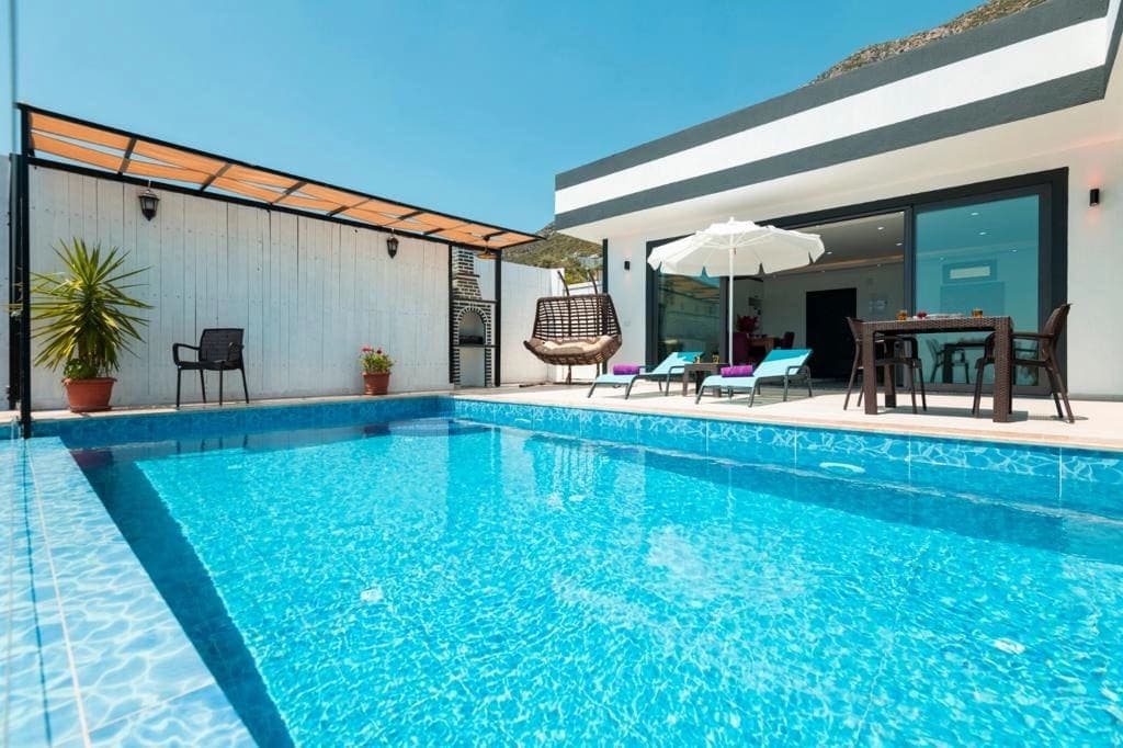 Özel yüzme havuzu ve şezlongların yer aldığı villa bahçesi.
