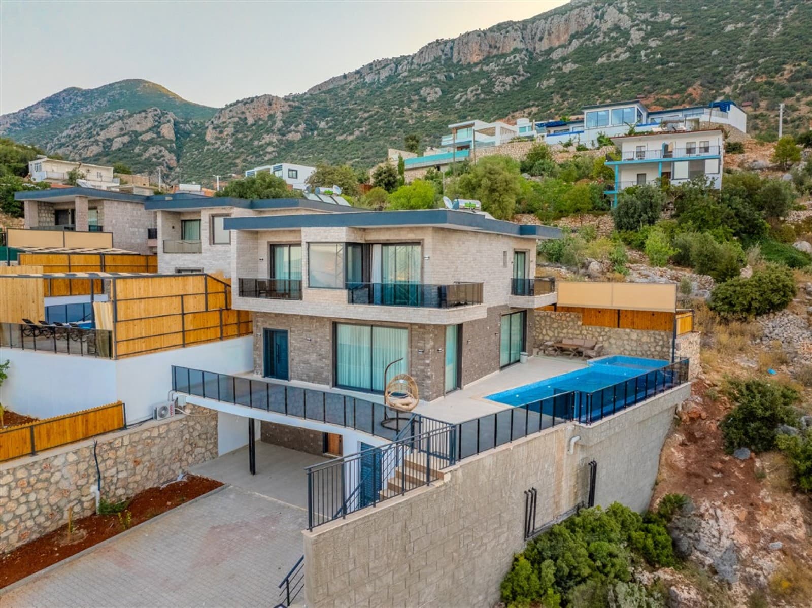 Dağ yamacına kurulu, havuzlu ve teraslı modern taş dış cepheli dubleks villa.