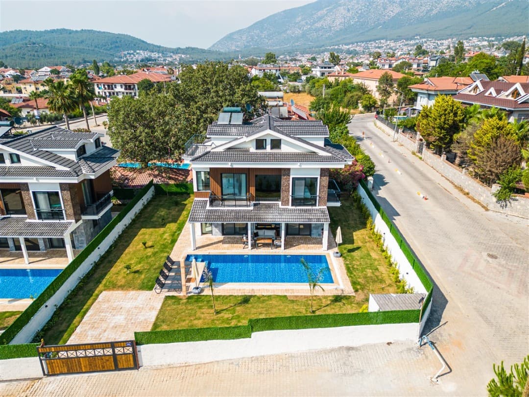 Bahçesinde havuz ve şezlonglar bulunan iki katlı villa
