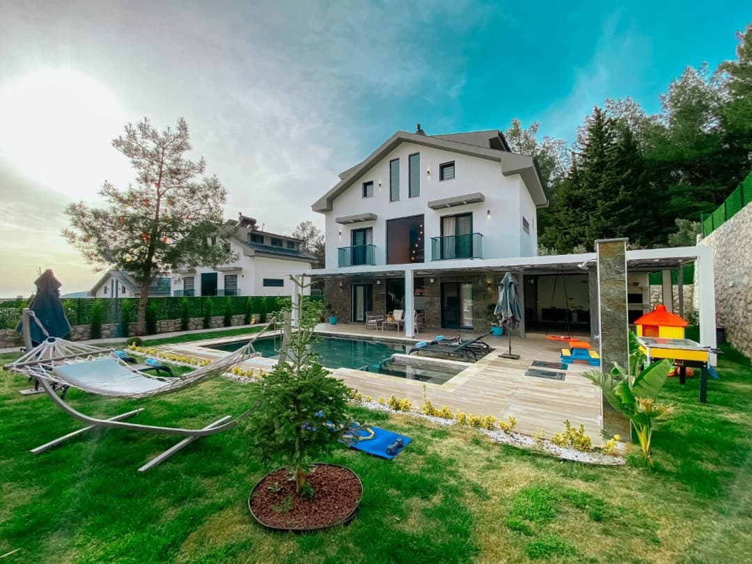 Bahçesinde havuz ve salıncak olan beyaz dış cepheli villa