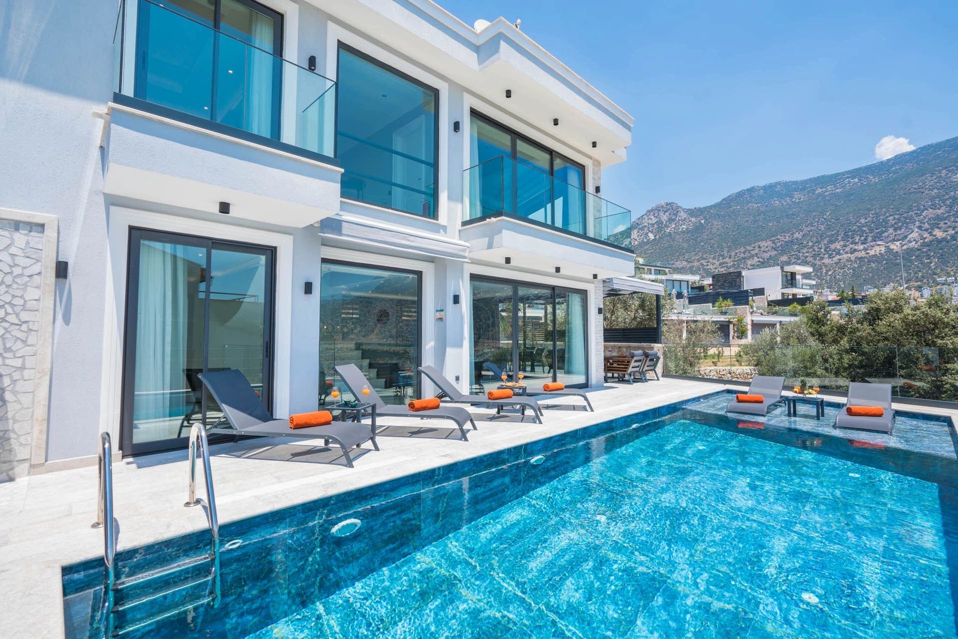 Havuz kenarında şezlonglar bulunan modern villanın dış cephesi