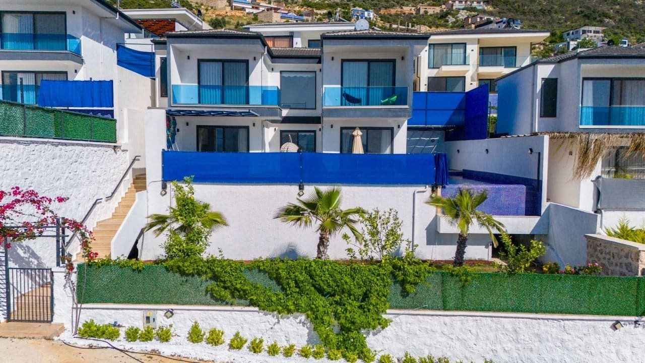 Bahçeli ve havuzlu çok katlı modern villa dış cephesi.