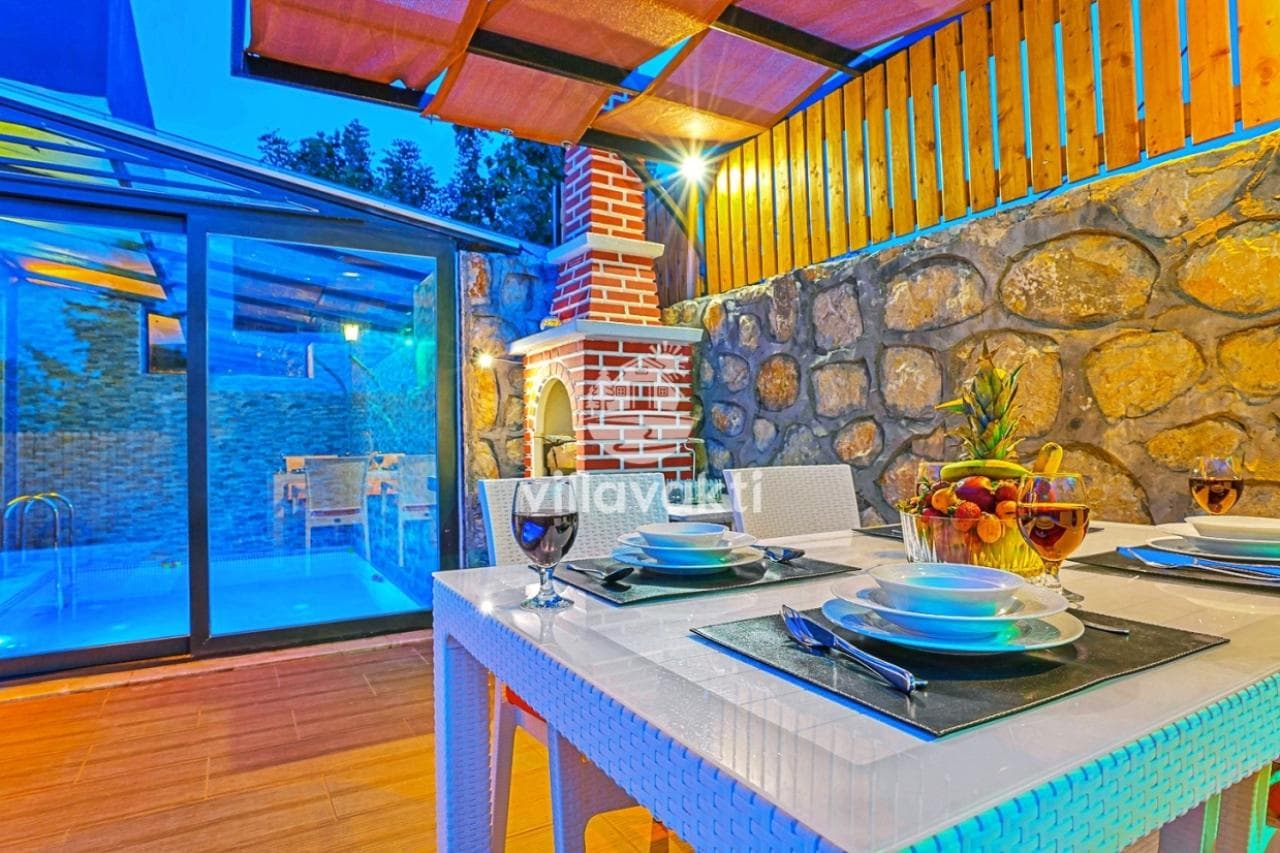 Verandada servis yapılmış yemek masası ve havuz kenarı.