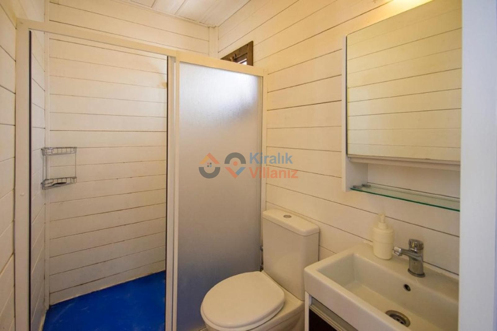 Ahşap duvarlı, duşakabinli ve lavabolu küçük banyo.