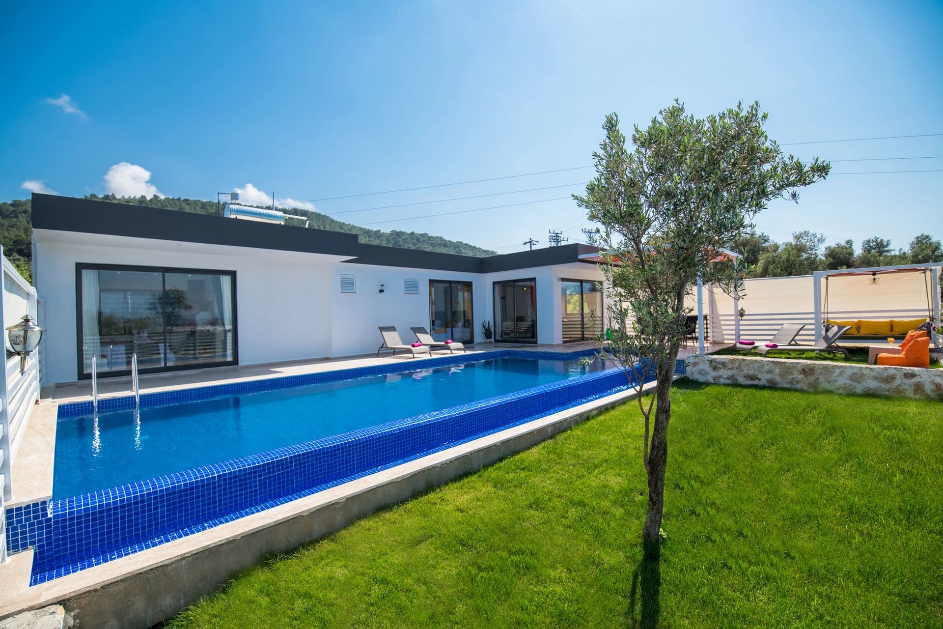 Geniş bahçesi ve yüzme havuzu bulunan beyaz villa dış cephesi.
