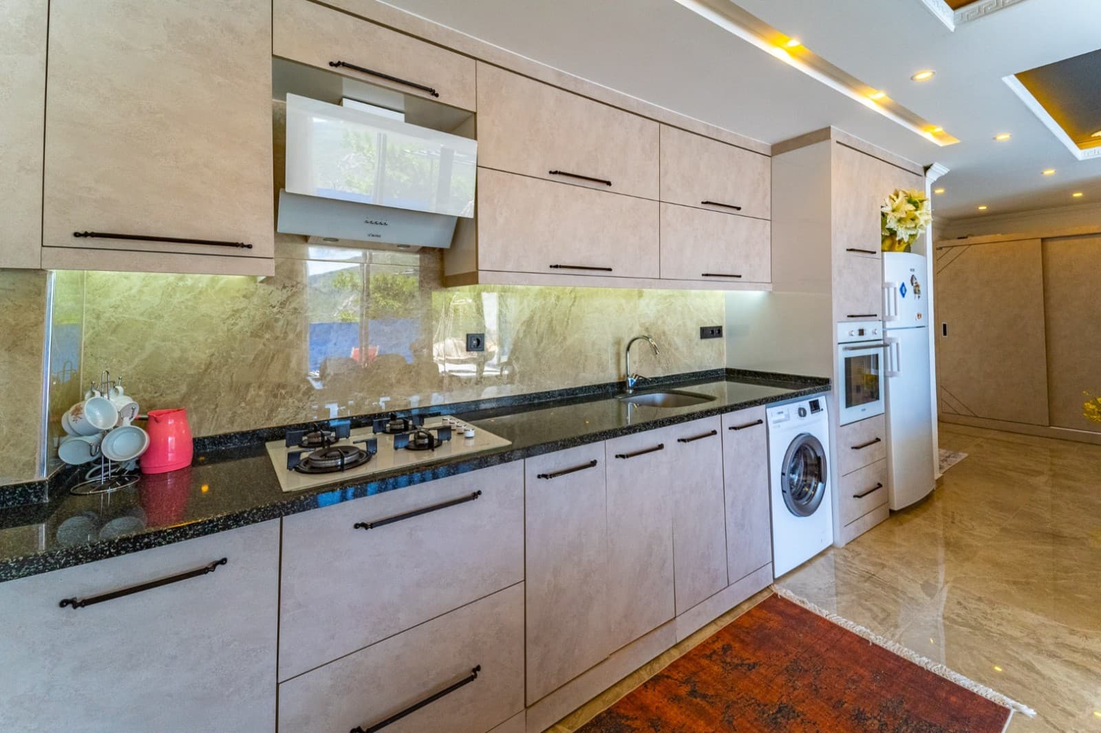 Bej dolaplı ve siyah tezgahlı modern mutfak iç mekanı.