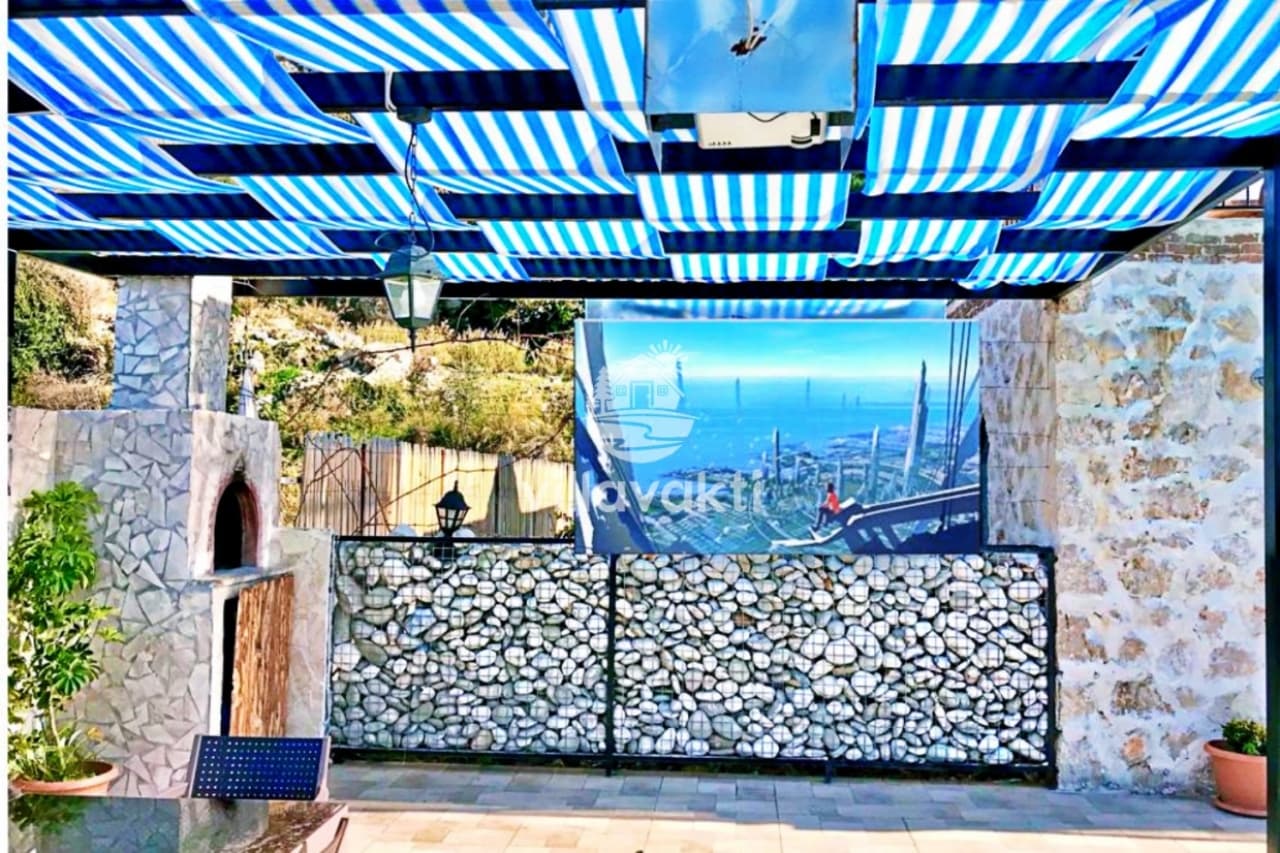 Taş duvarlı ve mavi-beyaz çizgili tenteli veranda alanı.