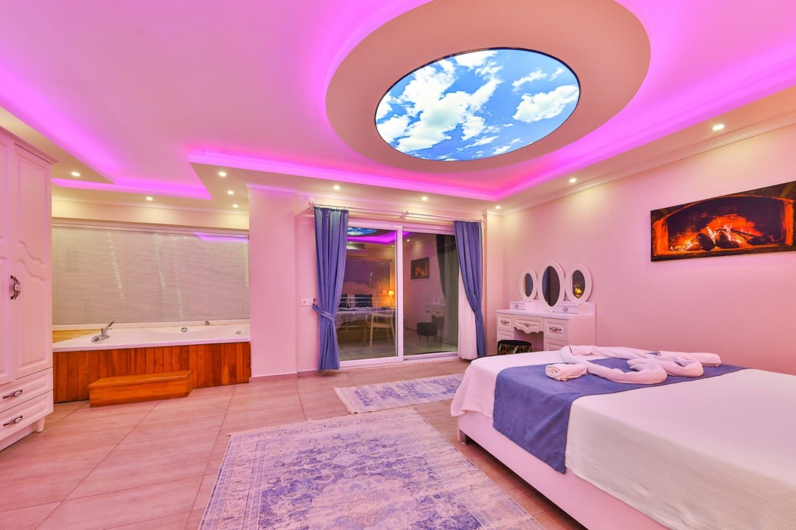 Pembe ışıklandırmalı yatak odasında jakuzi ve tavan detayları.