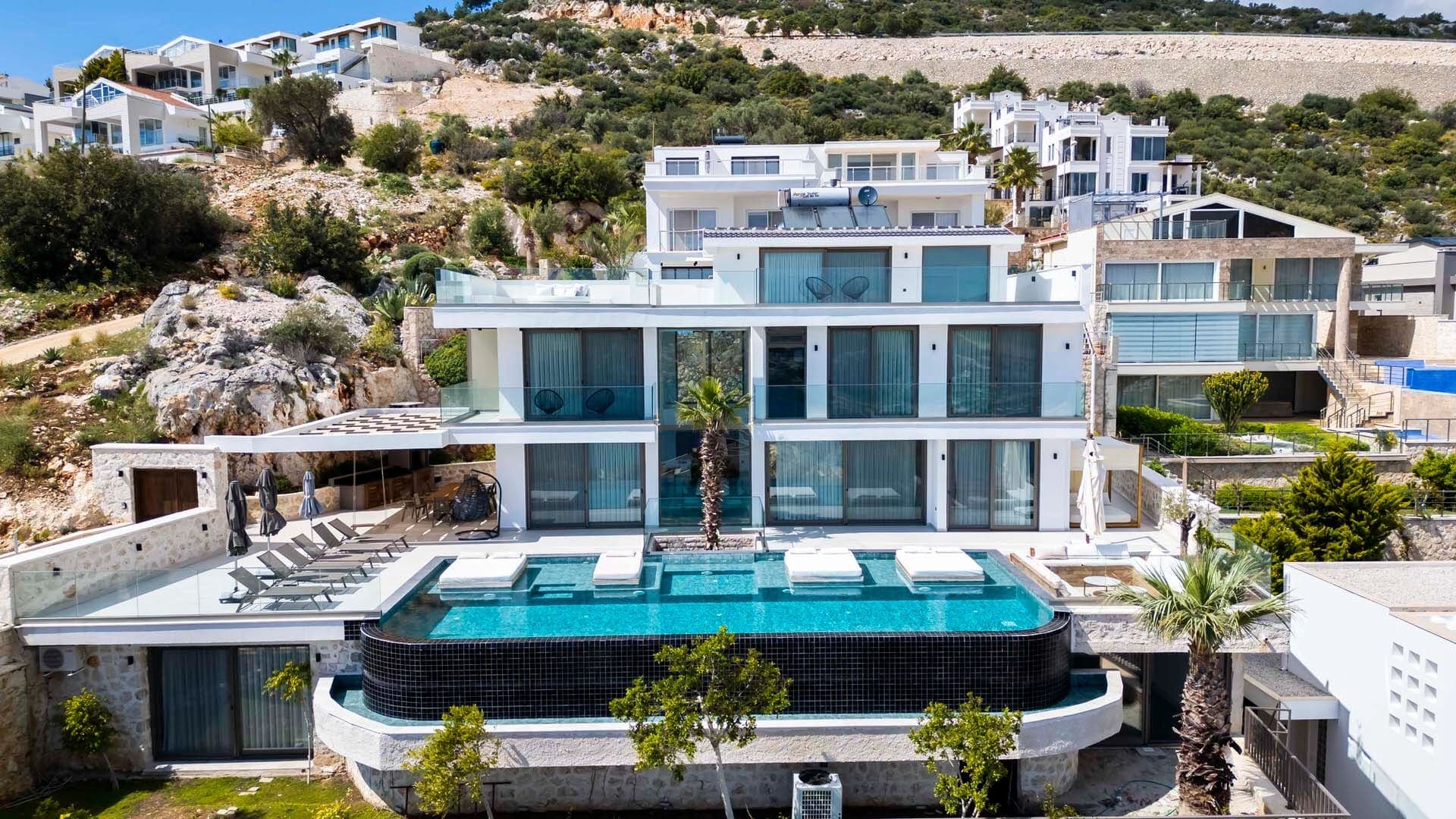 Dağ eteklerindeki modern villanın havuzlu ve teraslı dış cephesi.