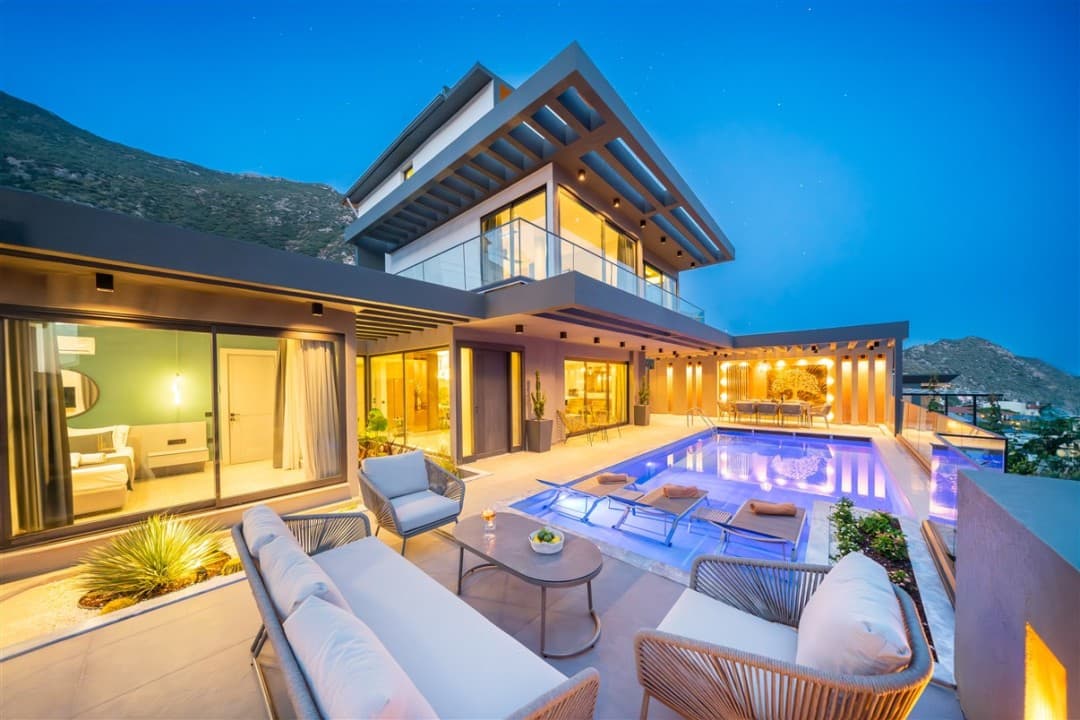 Akşam saatlerinde havuzlu ve aydınlatmalı modern villanın dış cephesi ve terası.