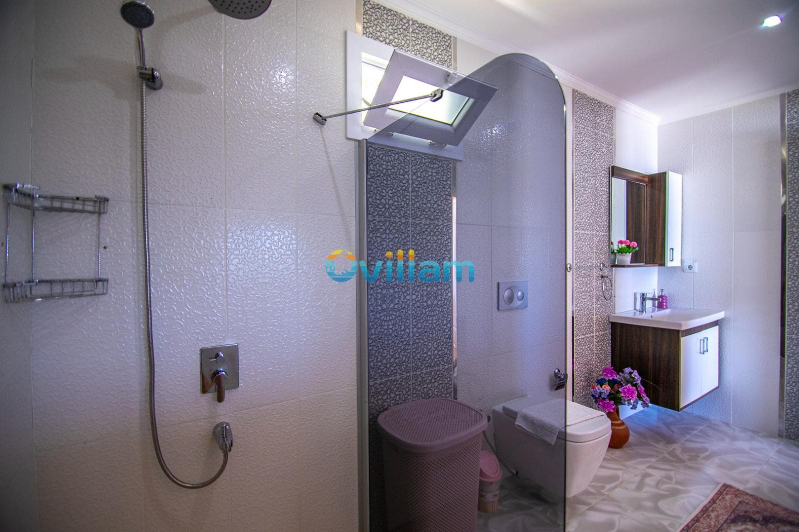 Açık renkli seramik kaplı duş alanı ve klozetin bulunduğu banyo.