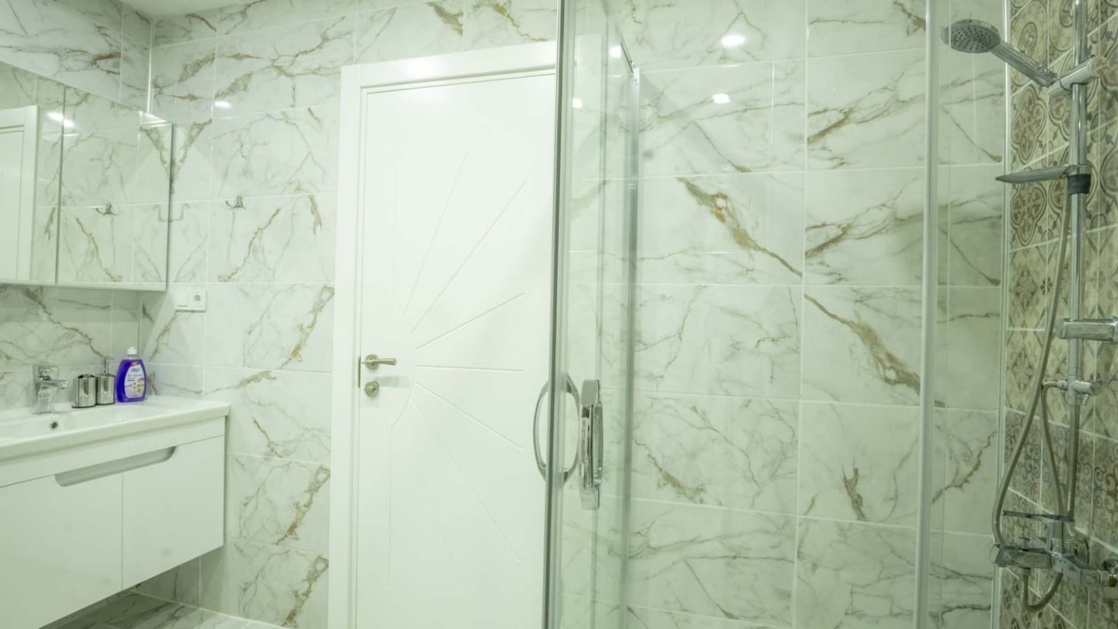 Mermer desenli duvar karolarına sahip duşakabinli banyo.
