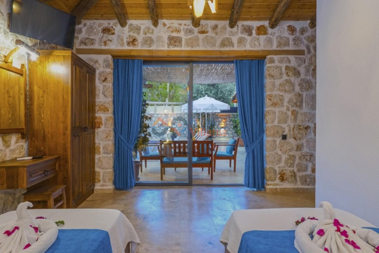 Taş duvarlı yatak odasından havuz terasına açılan cam kapı.