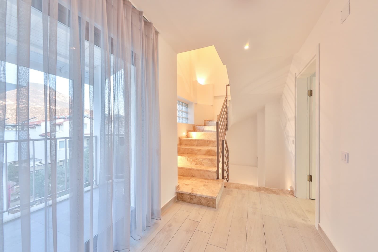 Balkon kapısı önünde tül perde ve kata çıkan mermer merdivenler.