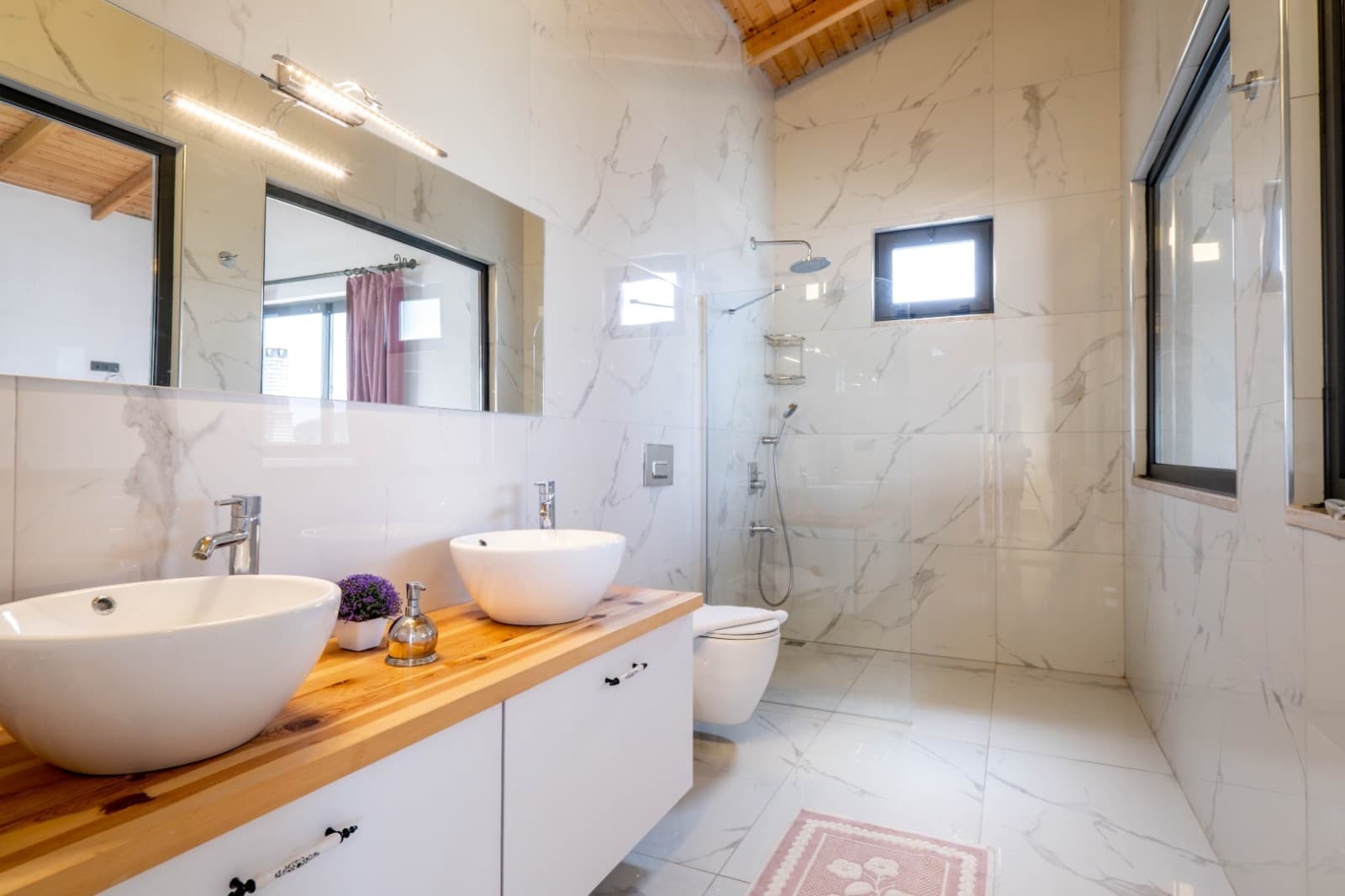 Mermer detaylı çift lavabo ve duşakabin bulunan modern banyo.