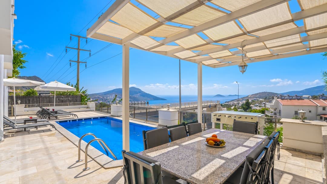 Deniz manzaralı terasta havuz, yemek masası ve ahşap pergola yer almaktadır.