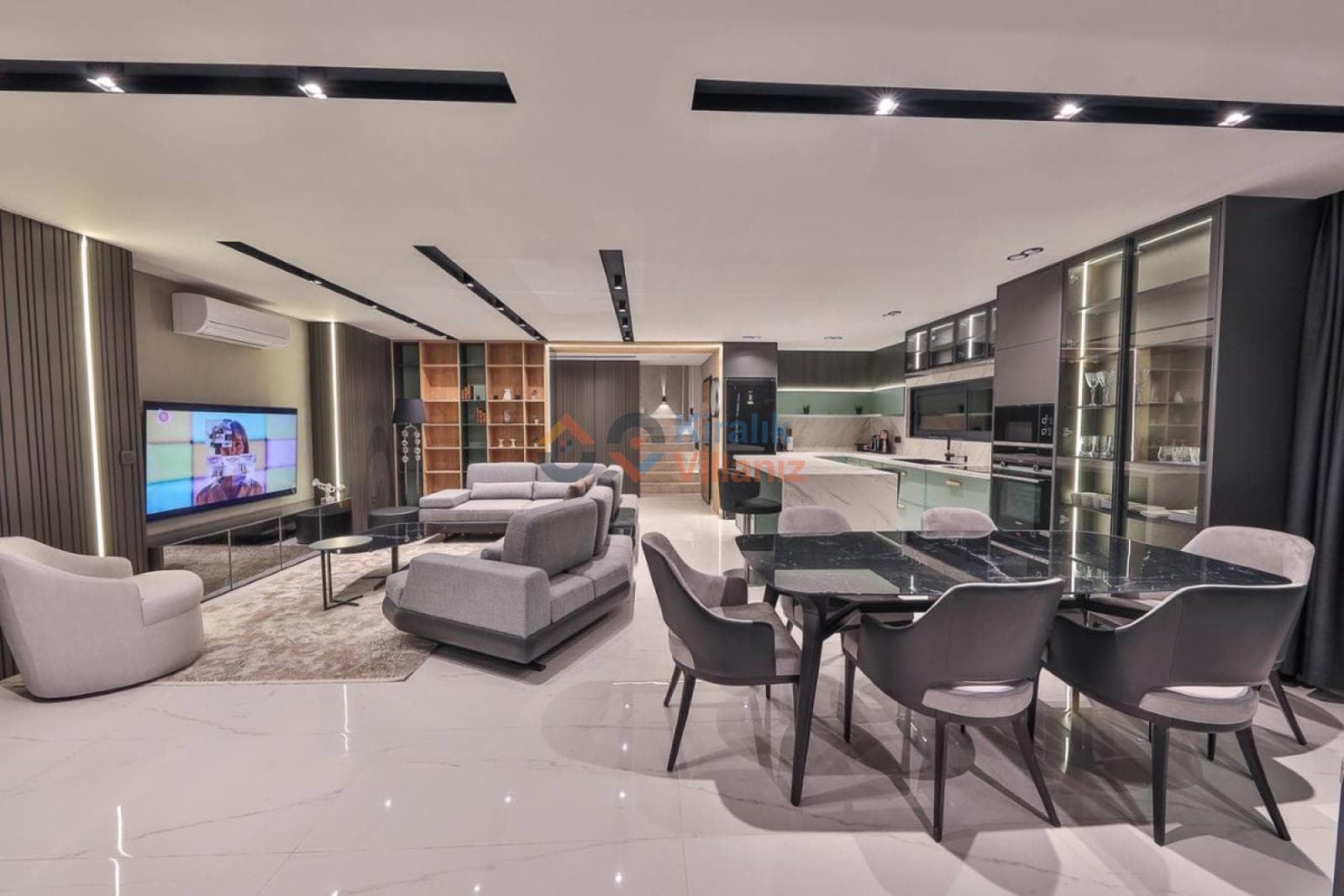Modern salon ve yemek odası alanında gri koltuk takımı, siyah yemek masası ve televizyon var.