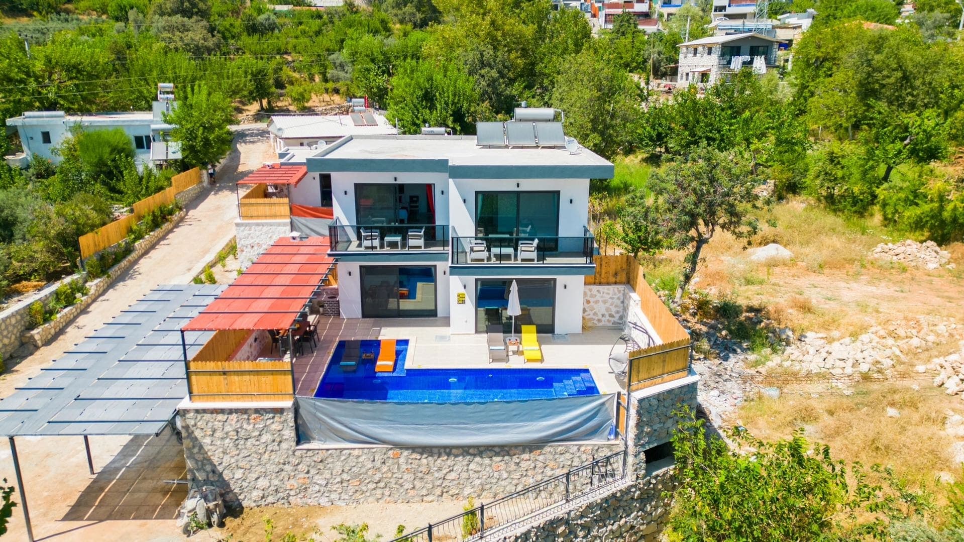 Önünde havuzu ve şezlongları bulunan iki katlı villa.