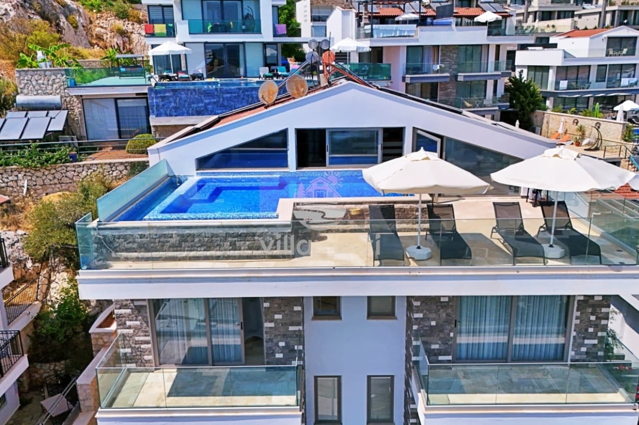 Çatısında havuz ve şezlonglar bulunan modern çok katlı villa.