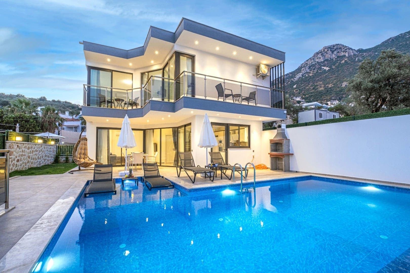 Dağ manzaralı modern villanın havuzu ve şezlonglu terası.