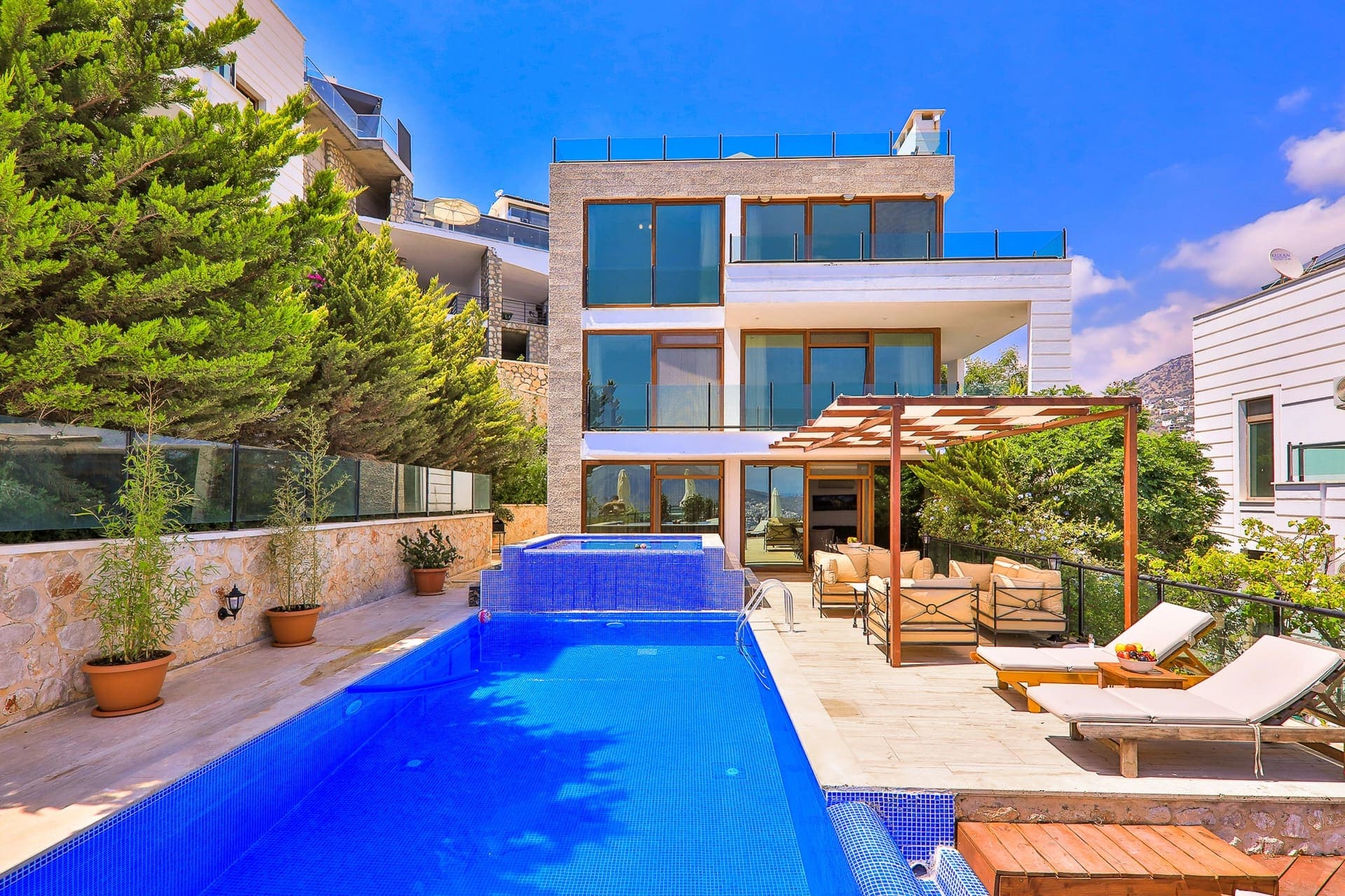 Bahçesinde havuz ve şezlonglar bulunan modern villa.
