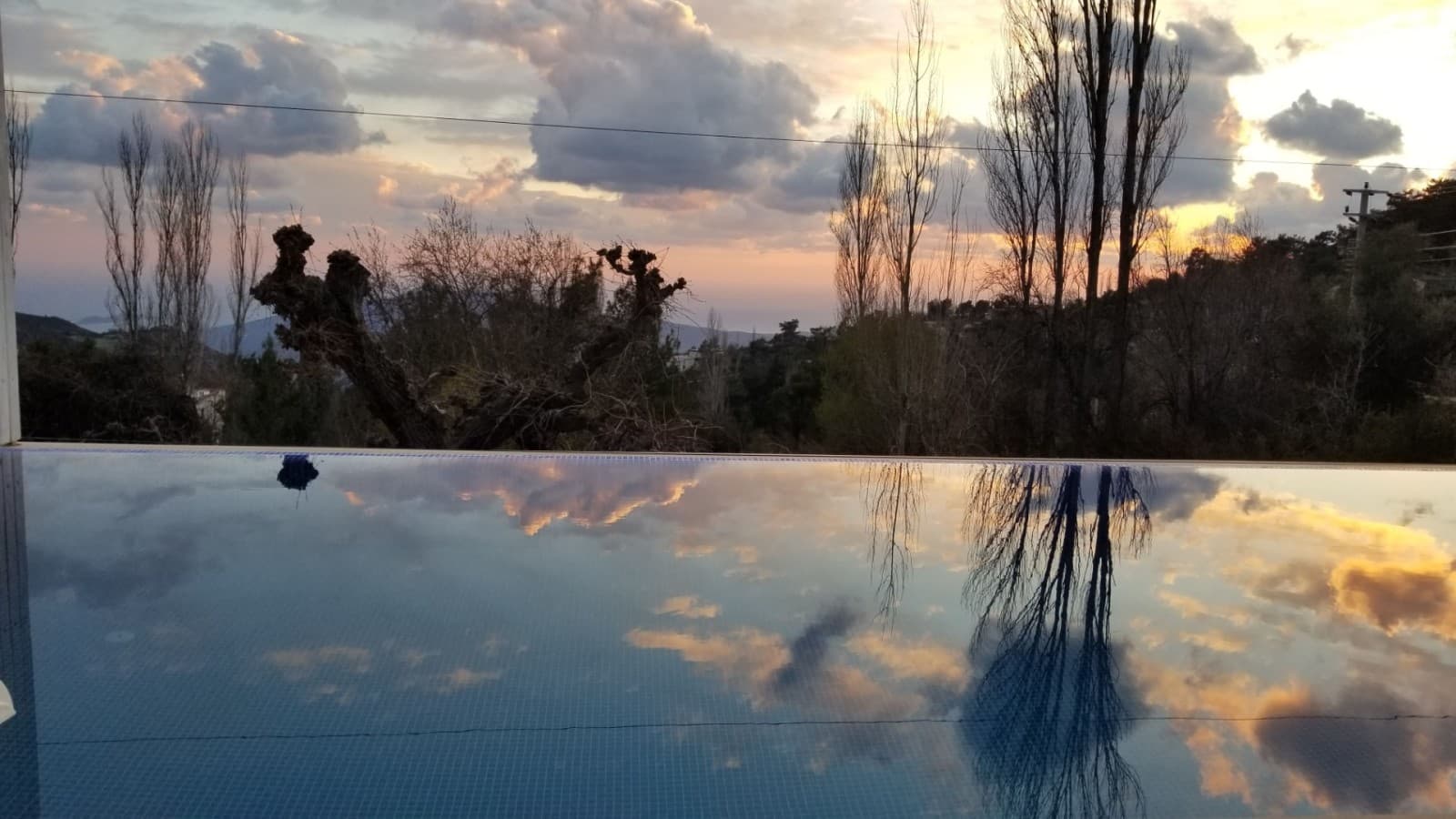 Havuz suyunda gün batımı ve bulutların yansıması.