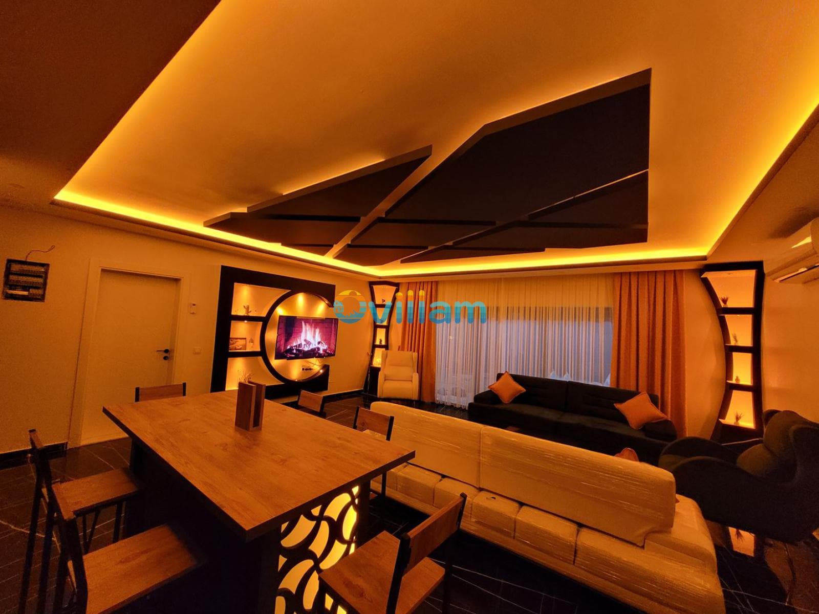 Sarı tonlarında aydınlatmaya sahip modern oturma odası ve yemek masası