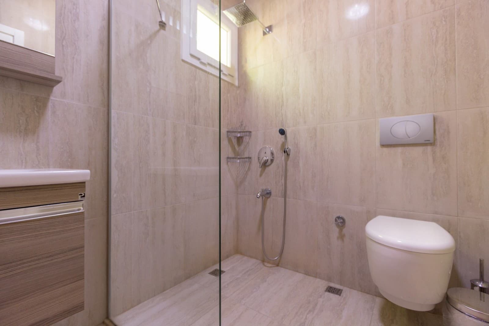 Bej seramik kaplı duş alanına sahip banyo ve klozet.