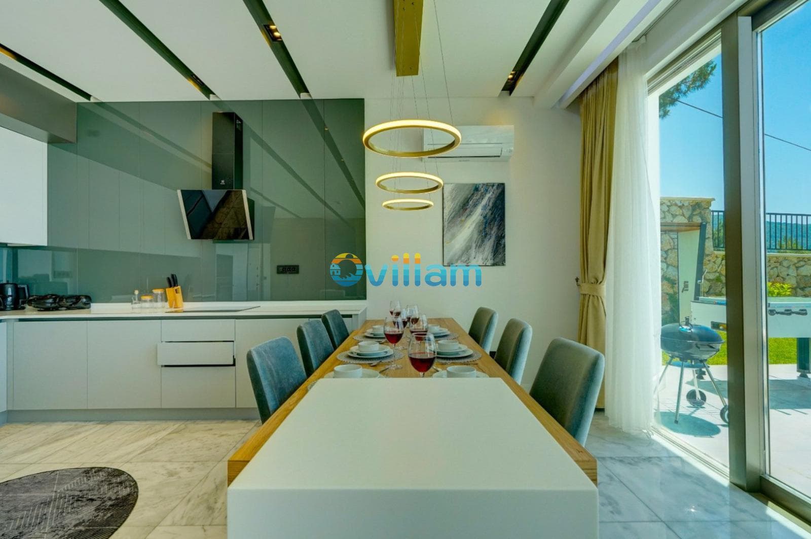 Modern mutfak ve uzun yemek masası bulunan iç mekân.