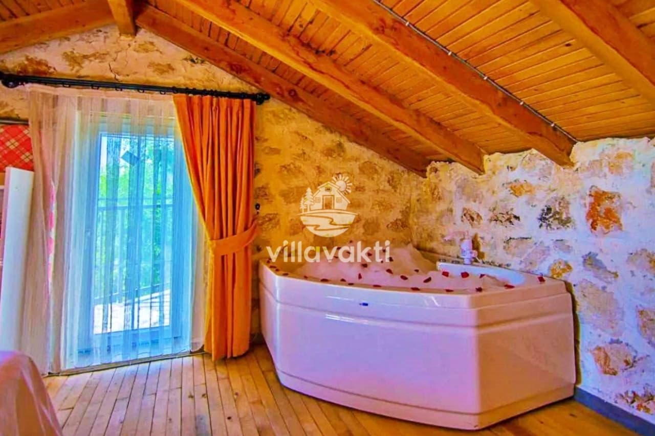 Ahşap çatılı tavanı olan odada jakuzi ve balkon kapısı.