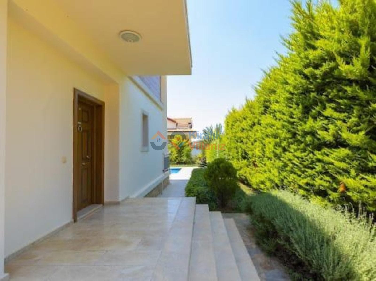Mermer merdivenli ve ahşap giriş kapılı villanın bahçe yolu.
