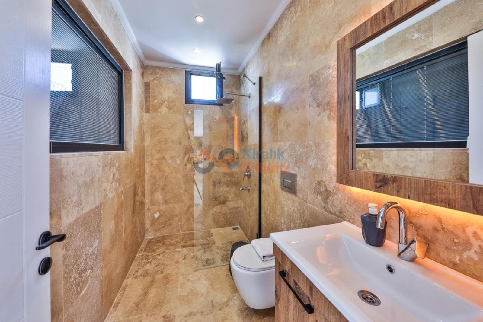 Bej seramik kaplı modern duş alanı ve lavabo.
