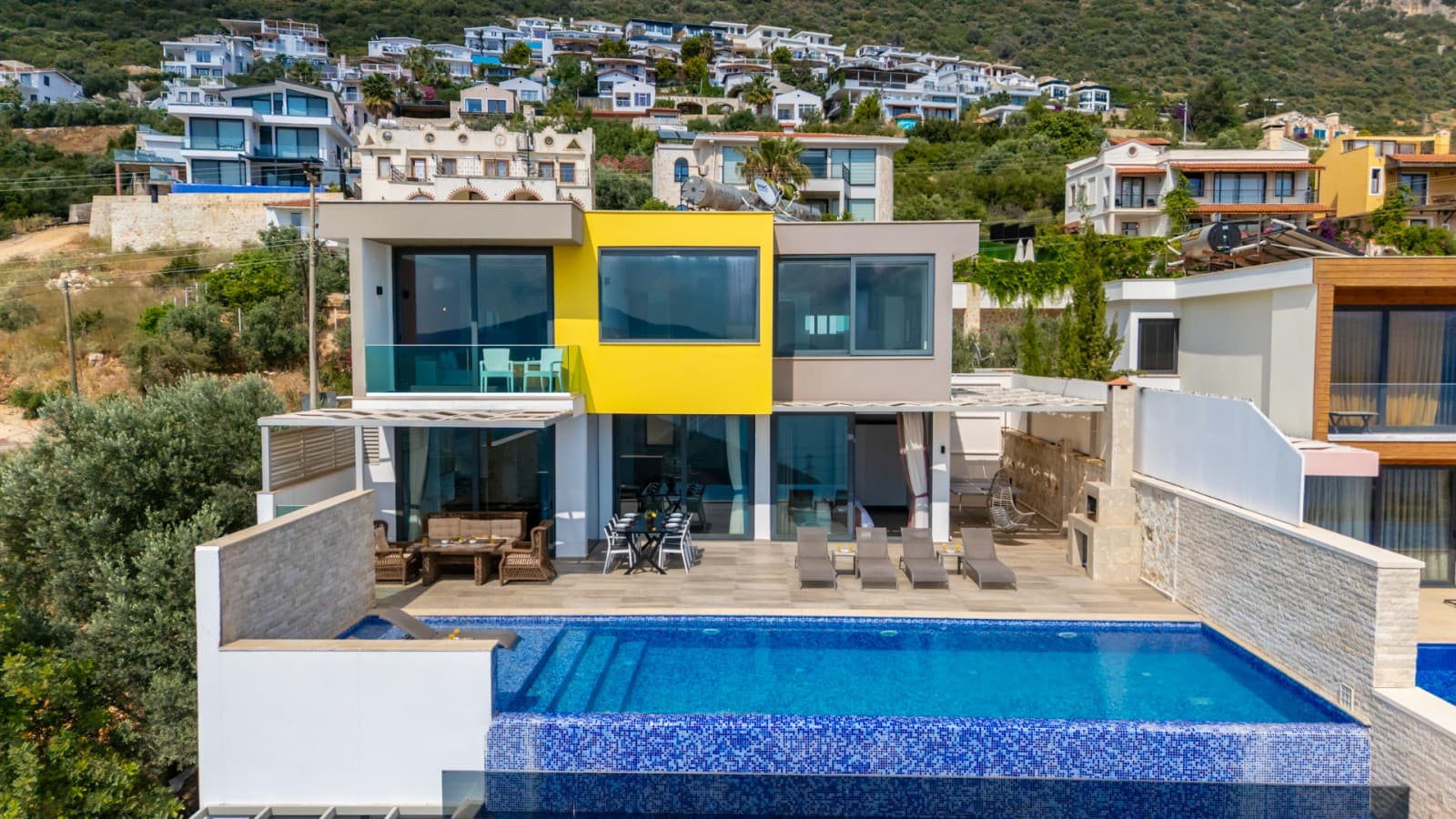 Havuzlu sarı detaylı villa ve arka planda yerleşim.