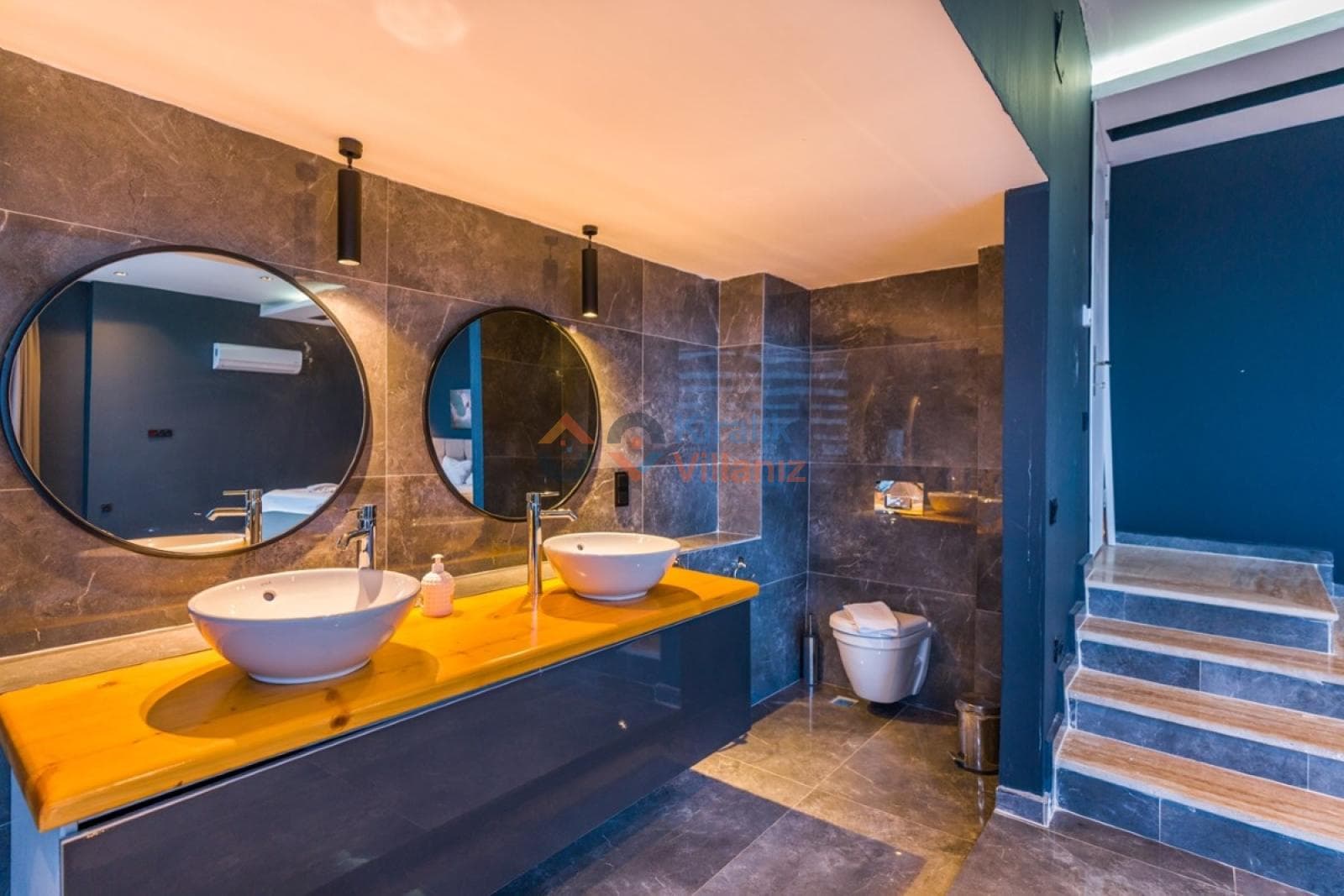 İki yuvarlak aynalı ahşap tezgâhlı çift lavabo ve asma klozetli banyo