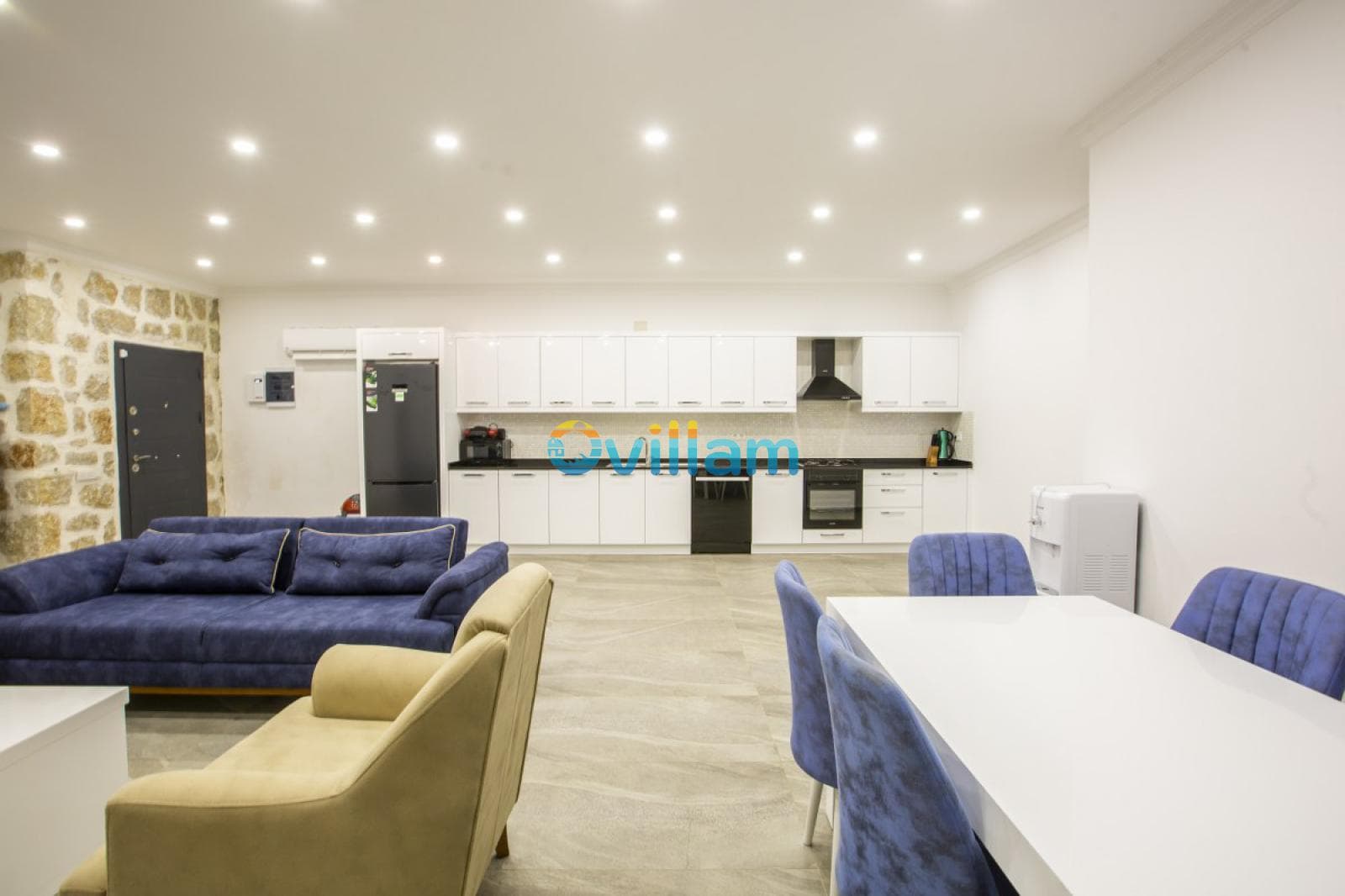 Taş duvar detaylı açık mutfak, salon ve yemek masası alanı.