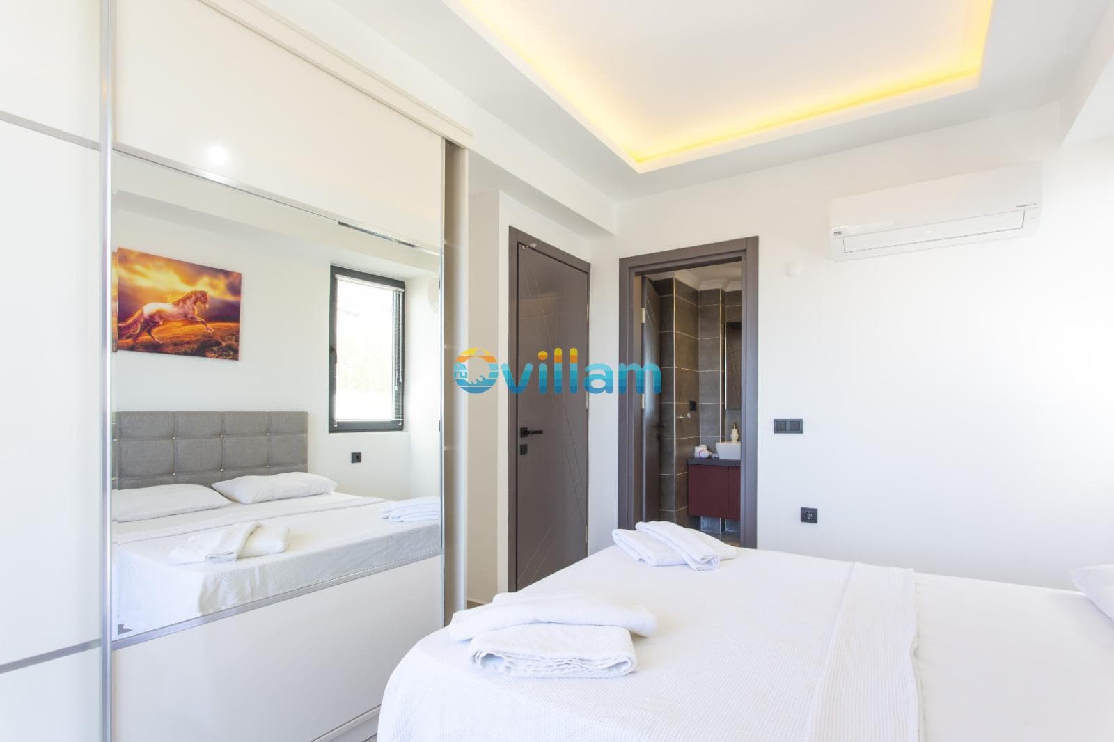 Beyaz yatak odasında çift kişilik yatak, gardırop ve banyo kapısı.