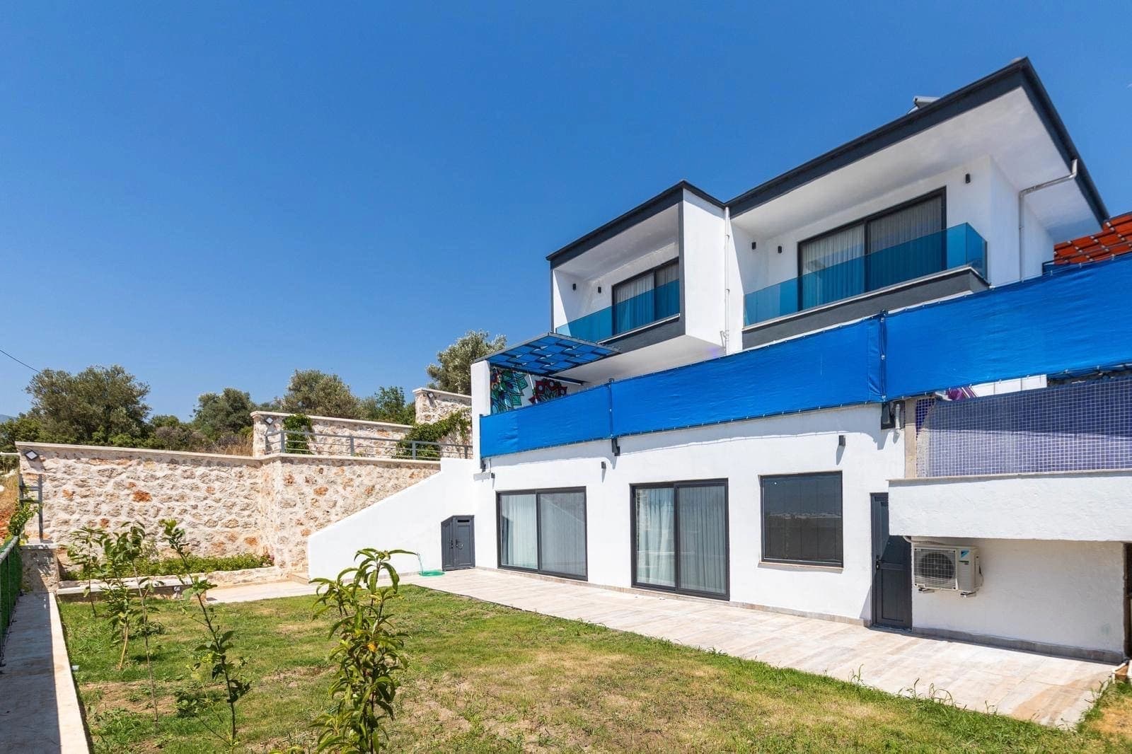 Bahçesi olan beyaz renkli iki katlı villanın dış cephe görünümü.