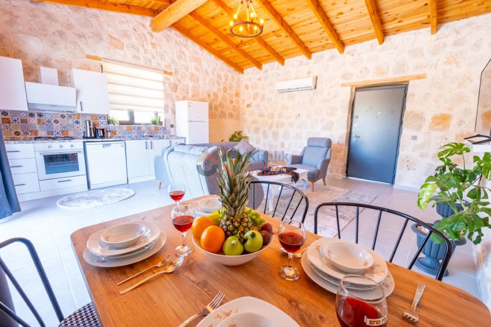 Taş duvarlı oturma alanı ve ön planda meyve tabağı olan yemek masası.