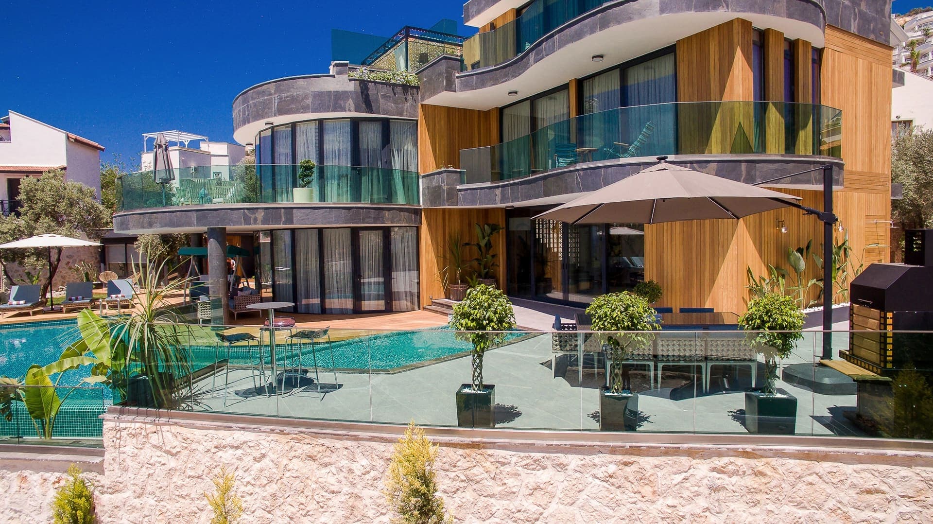 Cam balkonlu ve ahşap kaplamalı modern villanın havuzlu terası.