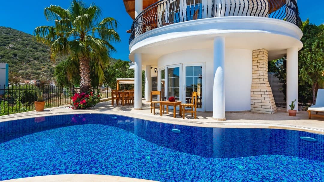 Kavisli balkonu ve havuzu bulunan beyaz villa.