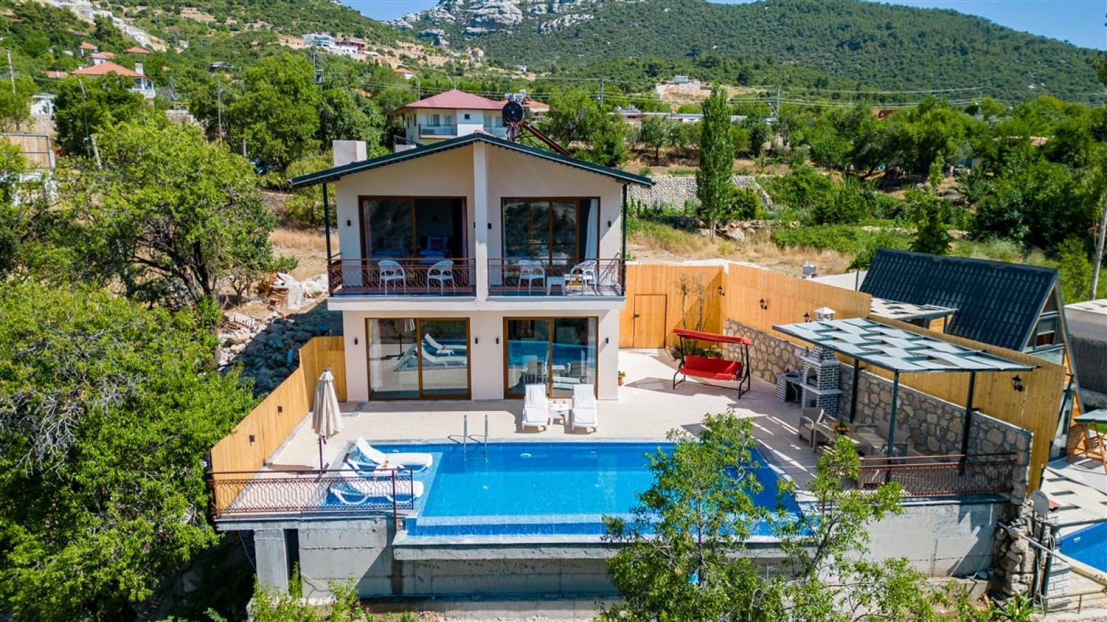 İki katlı, balkonlu ve havuzlu villanın dış cepheden görünümü.