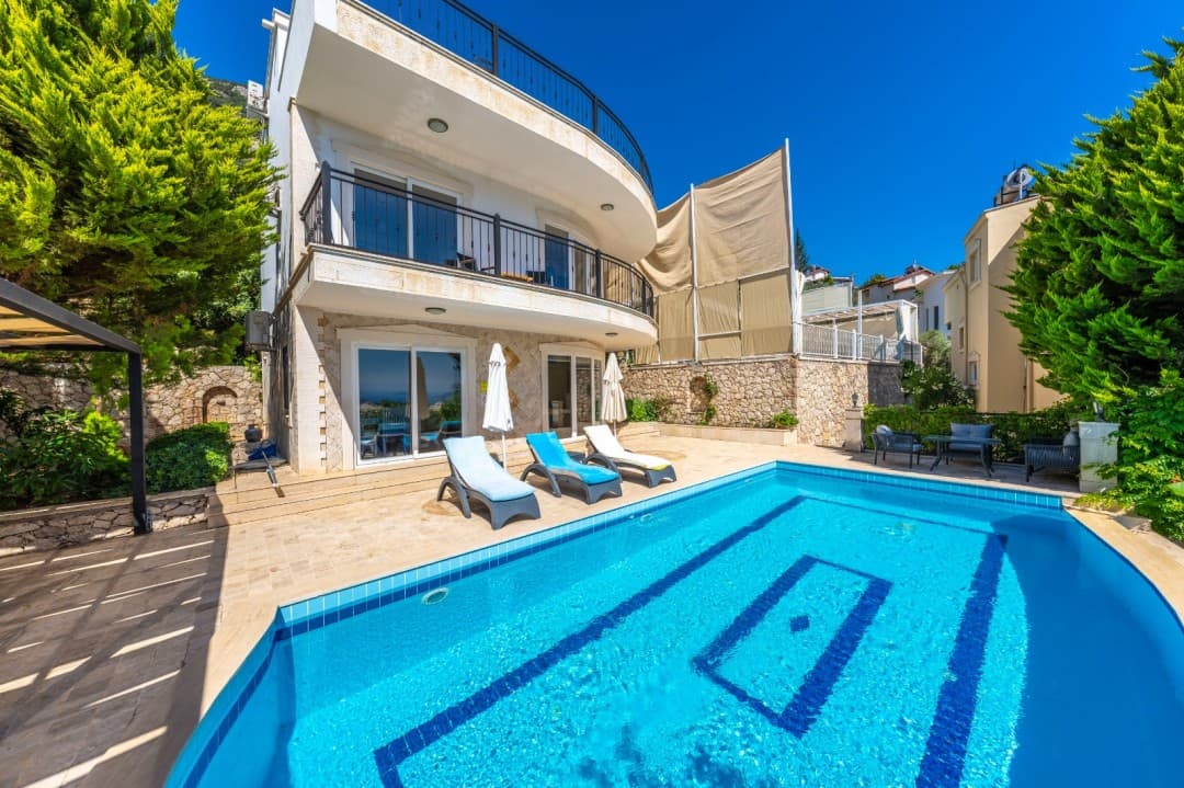 Geniş mavi havuzu ve şezlongları olan beyaz cepheli dubleks villa.