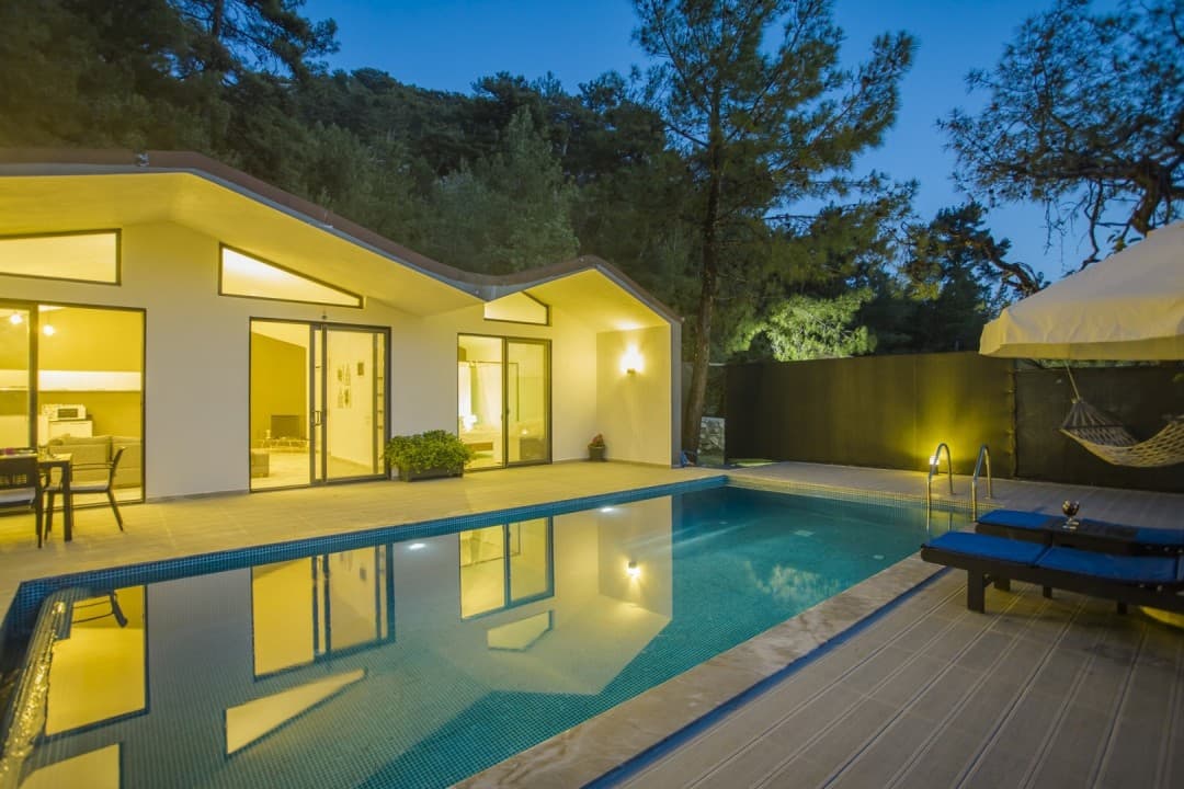 Akşamüstü havuzlu villa ve orman manzarası.