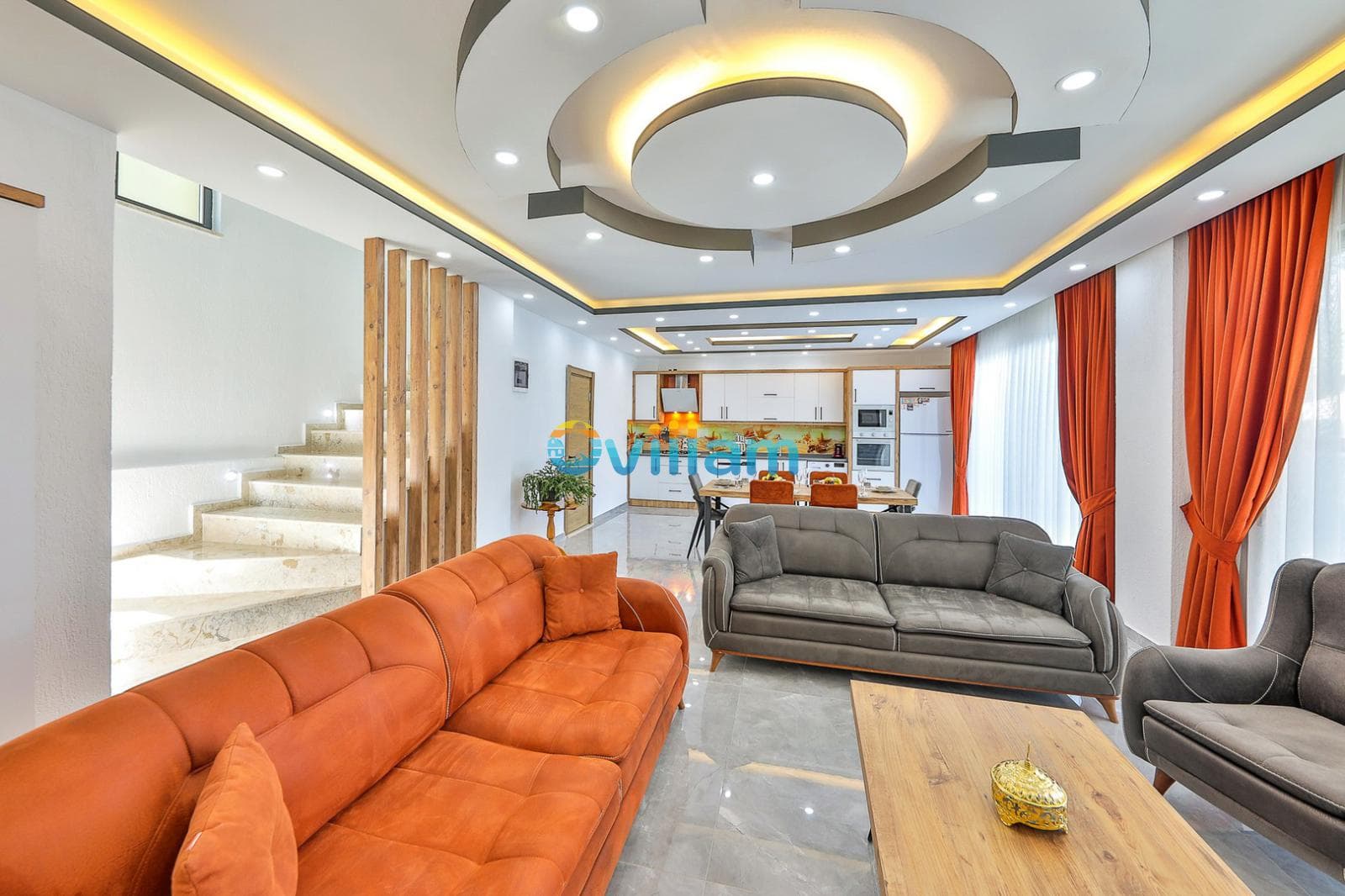 Turuncu koltuklar ve modern tavan aydınlatmasına sahip geniş oturma odası.