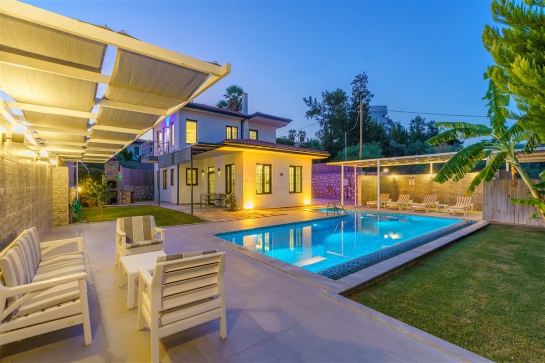 Akşam aydınlatmalı, bahçeli, havuzlu ve şezlonglu iki katlı müstakil villa.