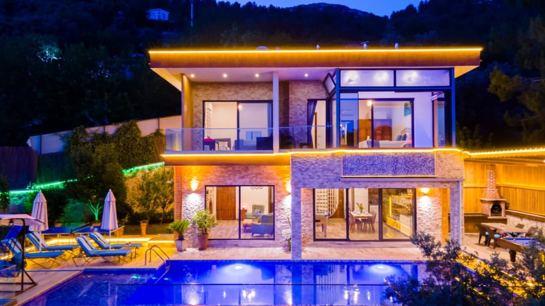 Akşam aydınlatmalı taş villa ve havuzu.